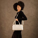 Pebbled Bone Oversized | Model holding mini duffle shaped handbag with crossbody strap