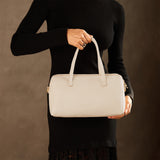 Pebbled Bone Oversized | Model holding mini duffle shaped handbag with crossbody strap