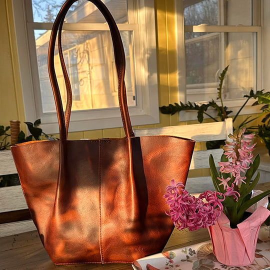Brown bag with an afternoon shadow on it sitting next to pink flowers