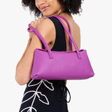Cattleya | Model wearing black dress carrying leather bowler bag with magnetic closure