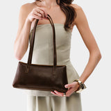 Coldbrew | Woman holding a dark brown leather bowler bag against a white background