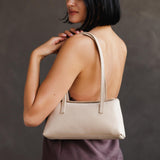 Dragon Bone | Woman wearing a white leather bowler bag against a white background
