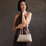 Dragon Bone | Woman wearing a white leather bowler bag against a white background