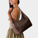 Lrg Aspen Shoulder Bag Mystery | Model holding u-shaped, flat-bottomed leather shoulder bag with adjustable strap