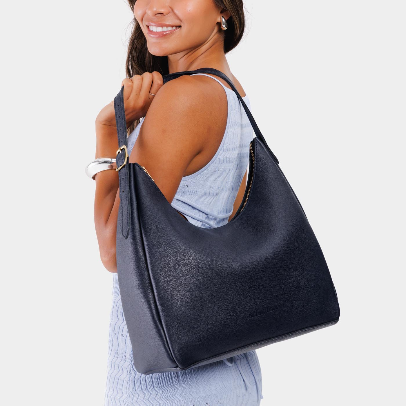 Night Owl*Large | Model holding u-shaped, flat-bottomed leather shoulder bag with adjustable strap