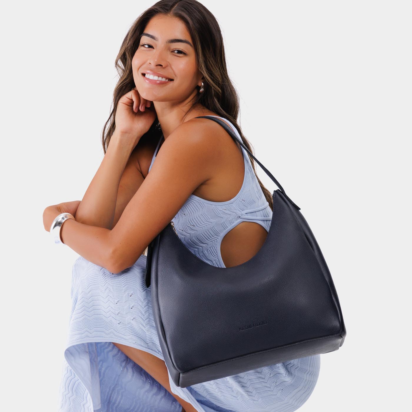 Night Owl*Large | Model holding u-shaped, flat-bottomed leather shoulder bag with adjustable strap