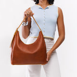 Sienna Large | Model holding u-shaped, flat-bottomed leather shoulder bag with adjustable strap