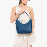 Caspian Medium | Model holding u-shaped, flat-bottomed leather shoulder bag with adjustable strap