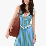 Nutmeg Oversized | Model carrying U-shaped, flat-bottomed leather shoulder bag with adjustable strap