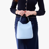 Skyway Large | Model holding symmetrical bucket bag with handle, latch closure, and removable crossbody strap