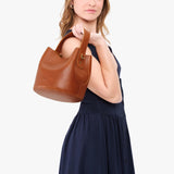 Honey Small | Model holding symmetrical bucket bag with handle, latch closure, and removable crossbody strap