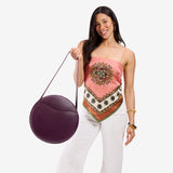 Plum | Model carrying large circle shaped leather bag with top zipper and carrying strap