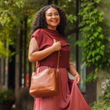 Meadow | Model wearing symmetrical bucket bag with latch closure and removable crossbody strap