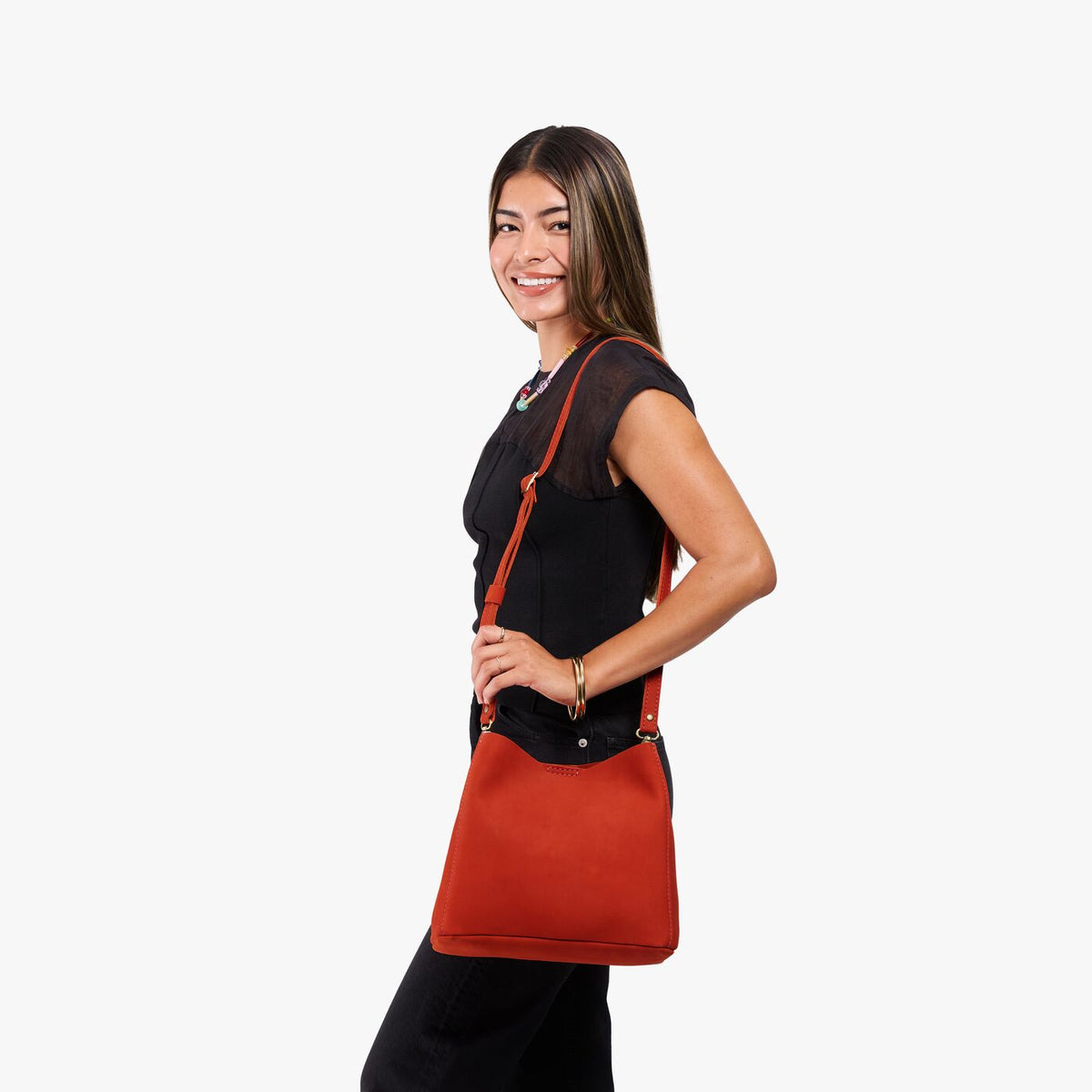 Paprika | Model wearing a symmetrical bucket bag with latch closure and removable crossbody strap