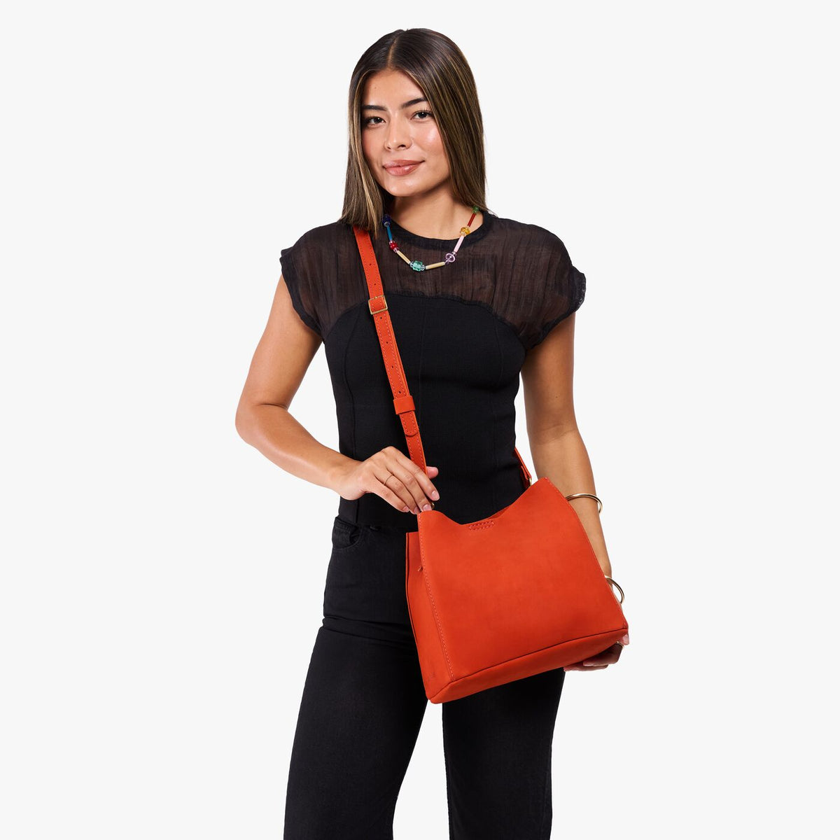 Paprika | Model wearing a symmetrical bucket bag with latch closure and removable crossbody strap
