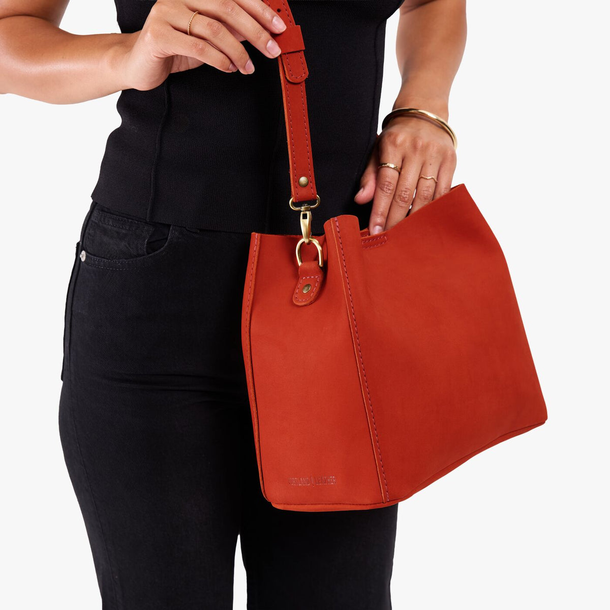 Paprika | Model wearing a symmetrical bucket bag with latch closure and removable crossbody strap