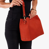 Paprika | Model wearing a symmetrical bucket bag with latch closure and removable crossbody strap