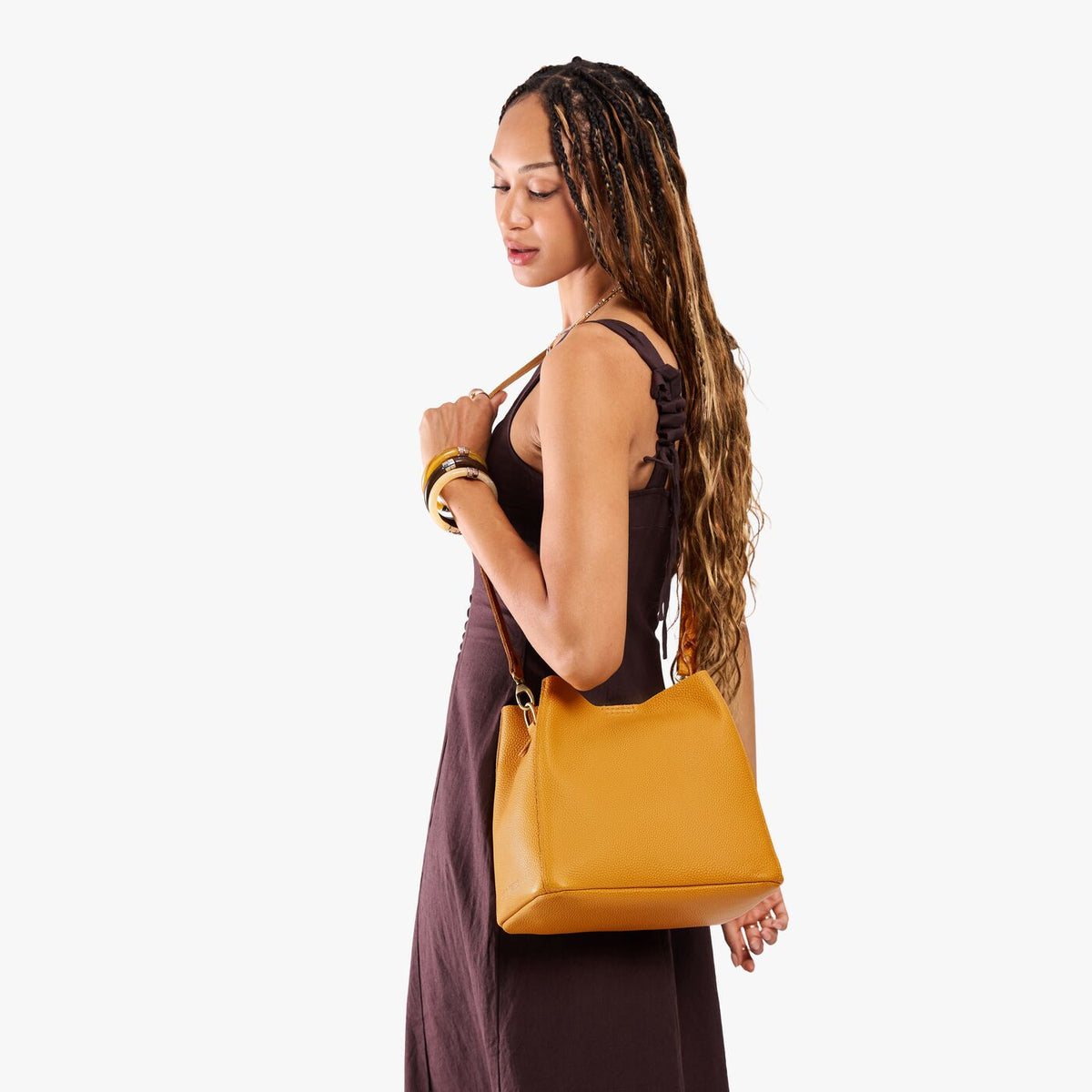 Sunshine | Model wearing a symmetrical bucket bag with latch closure and removable crossbody strap