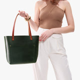 Evergreen Classic | Model holding large leather tote bag with sturdy bridle handles and front pocket