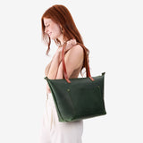 Evergreen Zipper | Model holding large leather tote bag with sturdy bridle handles and front pocket