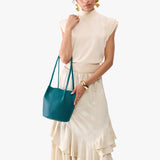 Aquarius Classic | Model wearing matching white shirt and skirt carrying petite bucket shaped tote bag with matching leather handles