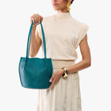 Aquarius Classic | Model wearing matching white shirt and skirt carrying petite bucket shaped tote bag with matching leather handles