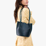 Boreal Classic | Model wearing matching light yellow shirt and trousers carrying petite bucket shaped tote bag with matching leather handles
