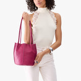Cosmo Small | Model wearing matching white sleeveless shirt and pants holding petite bucket shaped tote bag with matching leather handles