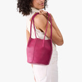 Cosmo Small | Model wearing matching white sleeveless shirt and pants holding petite bucket shaped tote bag with matching leather handles