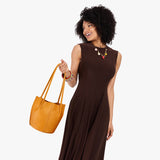 Sunshine Classic | Model wearing dark brown dress holding petite bucket shaped tote bag with matching leather handles