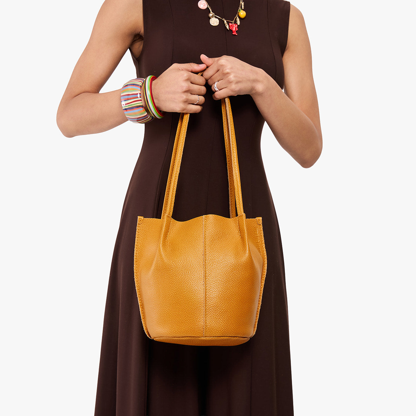 Sunshine*Classic | Model wearing dark brown dress holding petite bucket shaped tote bag with matching leather handles