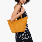 Sunshine Large | Model wearing black dress and carrying wide bucket shaped tote bag with matching leather handles