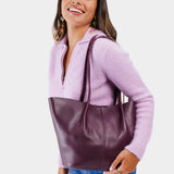 Plum Large | Model holding wide bucket shaped tote bag with matching leather handles