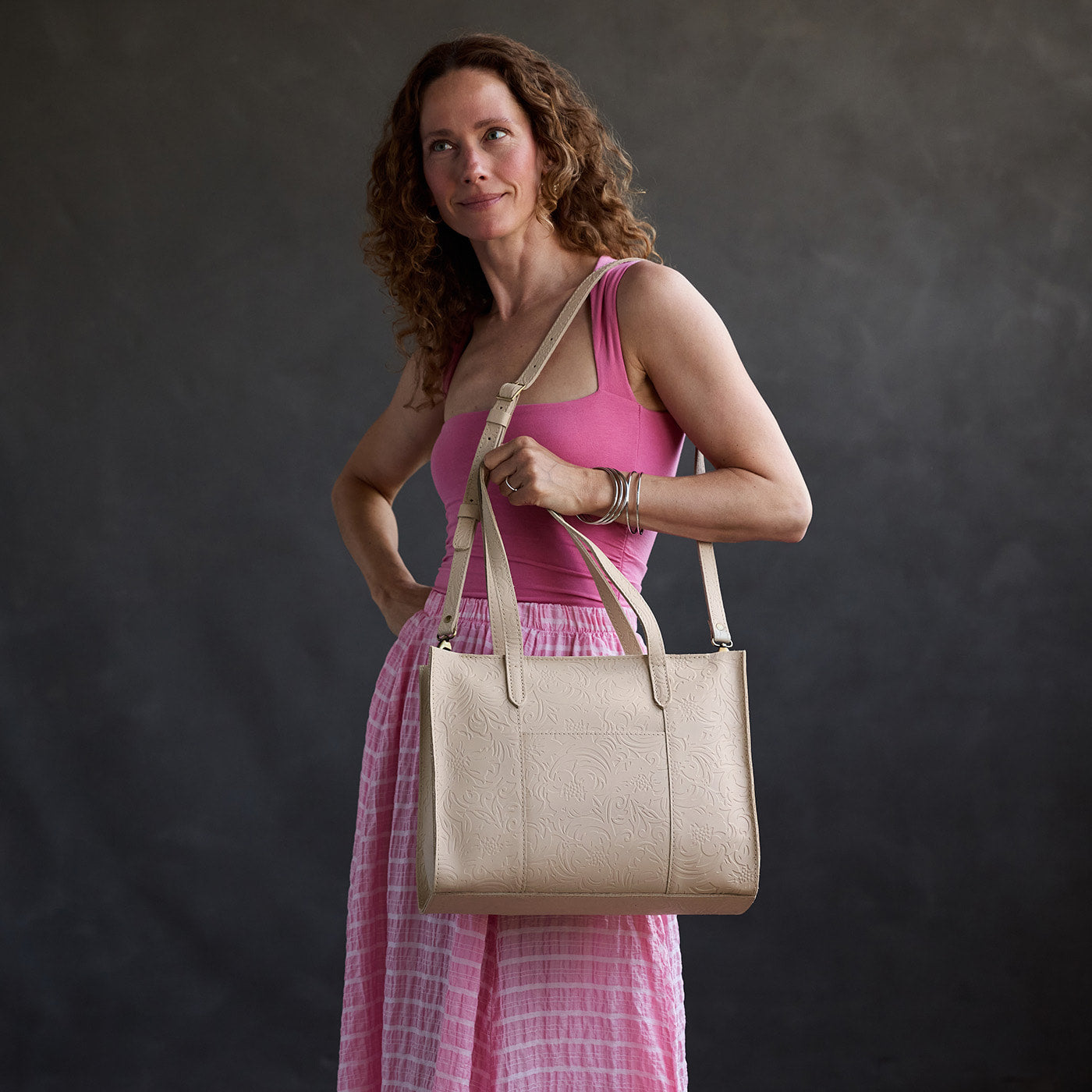 Jasmine | Model carrying structured wide embossed leather tote bag with overlapping panels and crossbody strap
