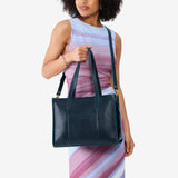 Boreal East/West | Model holding structured wide tote bag with overlapping panels and crossbody strap