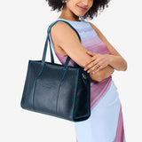 Boreal East/West | Model holding structured wide tote bag with overlapping panels and crossbody strap