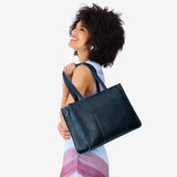 Boreal East/West | Model holding structured wide tote bag with overlapping panels and crossbody strap