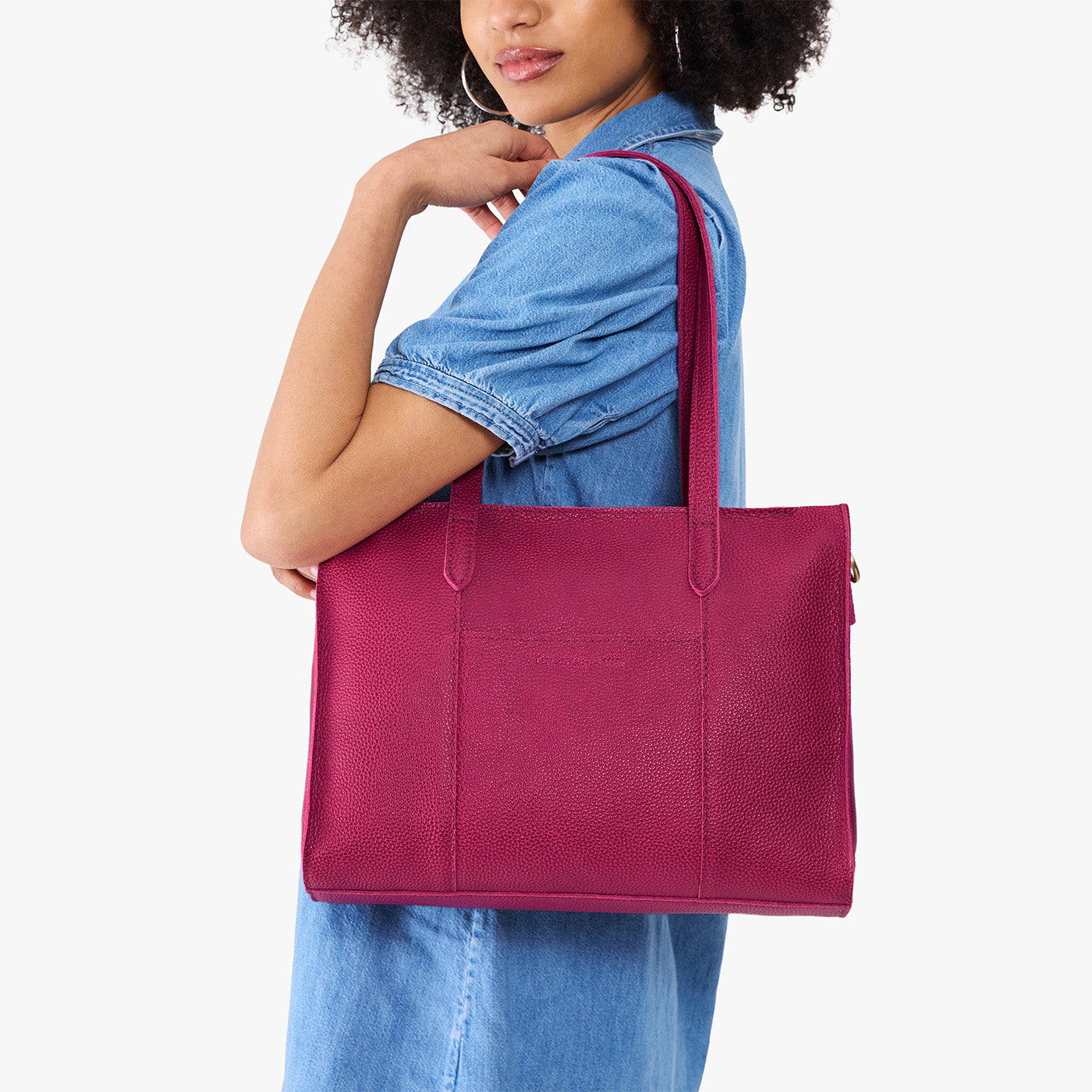Cosmo*East/West | Model holding structured wide tote bag with overlapping panels and crossbody strap