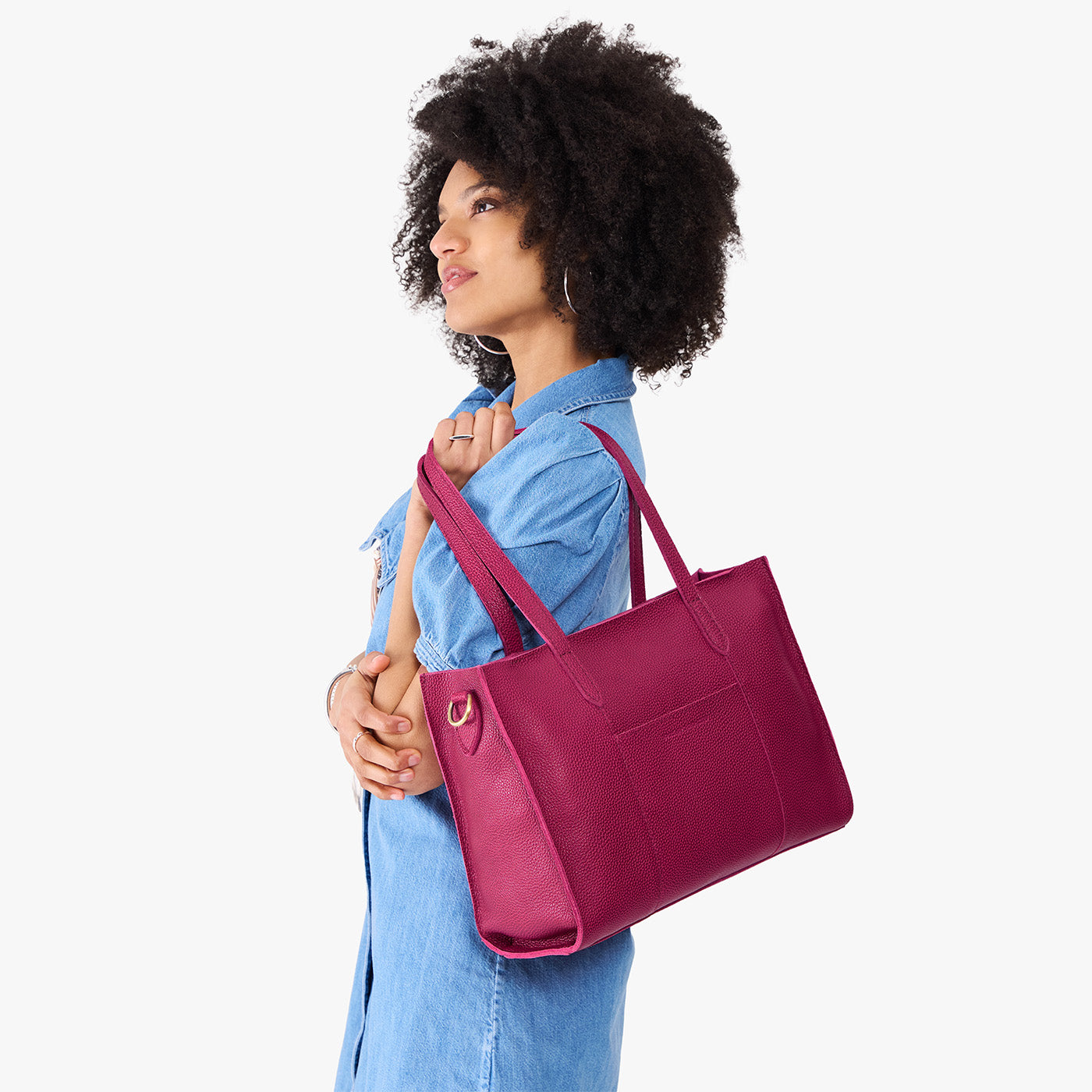 Cosmo*East/West | Model holding structured wide tote bag with overlapping panels and crossbody strap