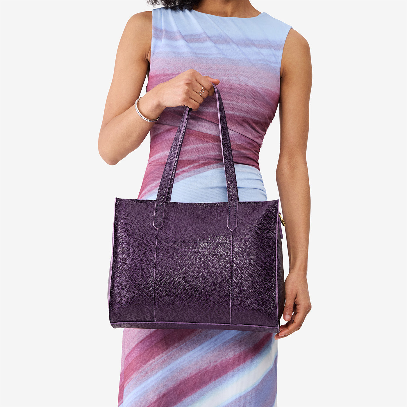 Empire*East/West | Model holding structured wide tote bag with overlapping panels and crossbody strap