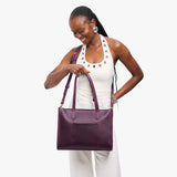 Larkspur East/West | Model holding structured wide tote bag with overlapping panels and crossbody strap