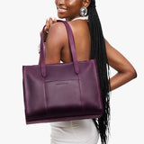 Larkspur East/West | Model holding structured wide tote bag with overlapping panels and crossbody strap
