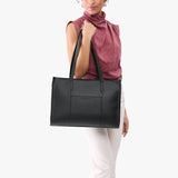 Black Oversized East/West | Model holding structured wide tote bag with overlapping panels and crossbody strap