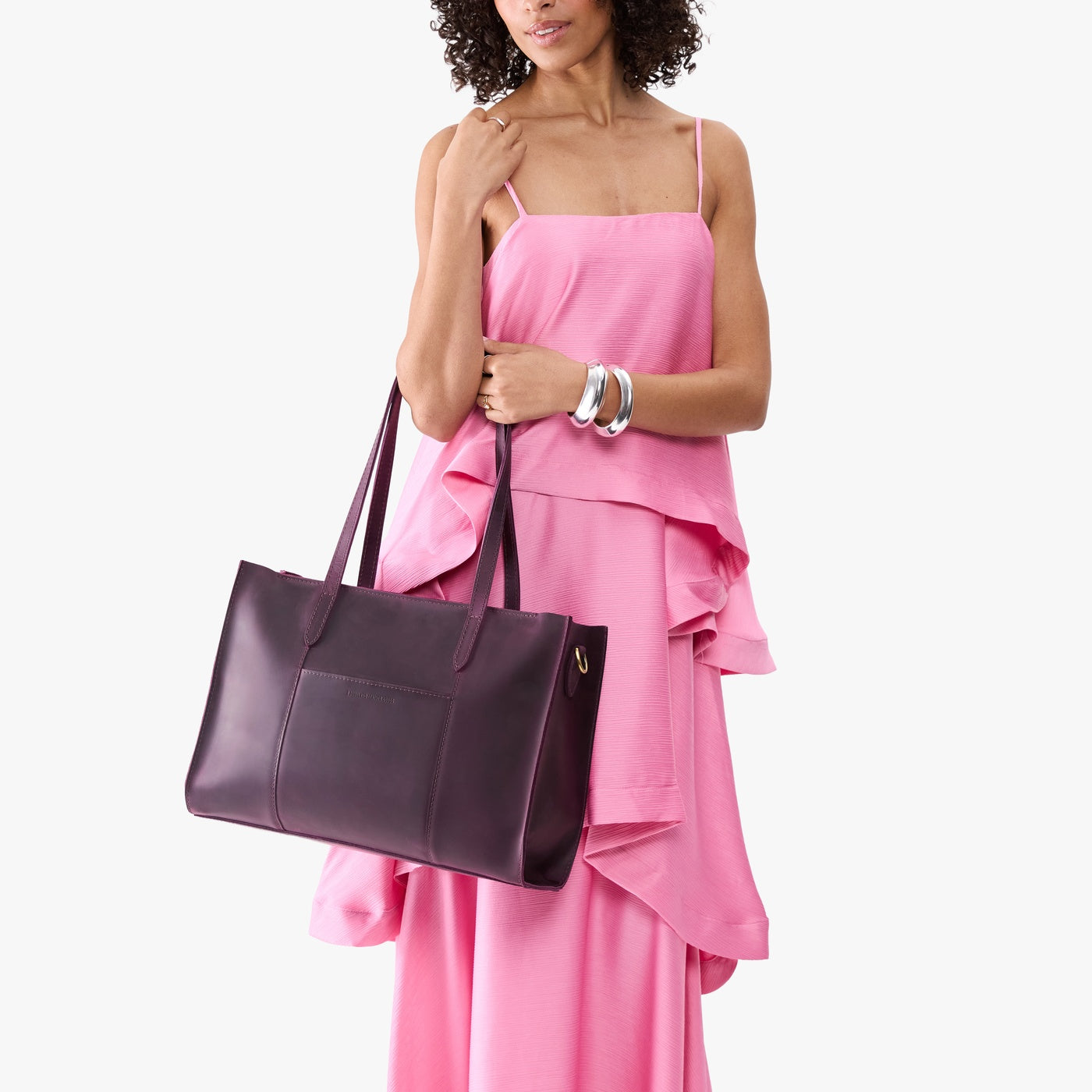 Larkspur*Oversized East/West | Model holding structured wide tote bag with overlapping panels and crossbody strap