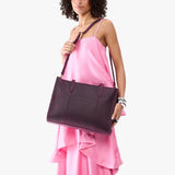 Larkspur Oversized East/West | Model holding structured wide tote bag with overlapping panels and crossbody strap