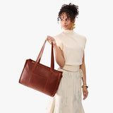 Nutmeg Oversized East/West | Model holding structured wide tote bag with overlapping panels and crossbody strap