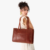 Nutmeg Oversized East/West | Model holding structured wide tote bag with overlapping panels and crossbody strap