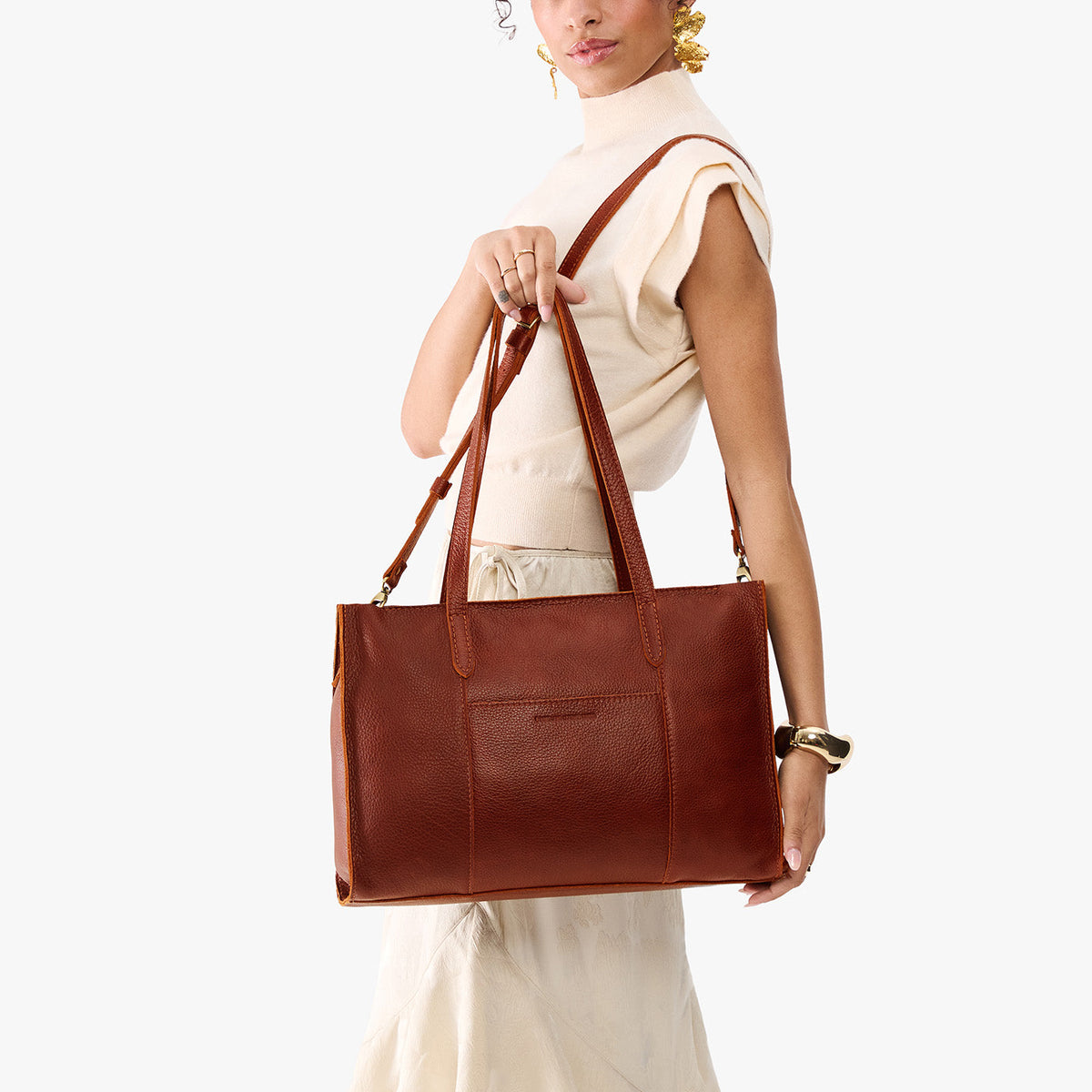 Nutmeg*Oversized East/West | Model holding structured wide tote bag with overlapping panels and crossbody strap