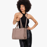 Sparrow East/West | Model holding structured wide tote bag with overlapping panels and crossbody strap