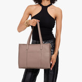 Sparrow East/West | Model holding structured wide tote bag with overlapping panels and crossbody strap